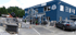 Blaues Gebäude von "trendy Jupiter Hamburg" mit Steinausstellung und einem parkenden grauen SUV.