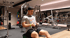 Ein Mann in Sportkleidung trainiert an einer Rudermaschine im Fitnessstudio zwischen Hantelscheiben und Kraftgeräten.