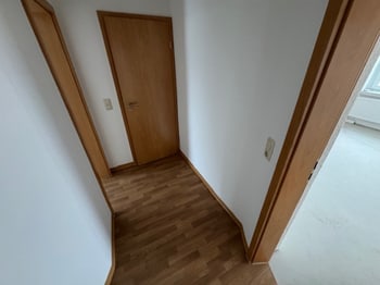 Leerer Flur mit braunen Türen und Laminatboden