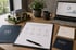 Schreibtisch mit Hausmodell, Laptop mit Finanzdiagrammen und Unterlagen der HB Finanz zur Immobilienfinanzierung.