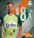 Ein lächelnder Handballspieler in einem grünen Trikot mit der Nummer 18 und dem Text „Licher“, umgeben von Sponsorenlogos.