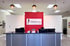 Jernigan Chiropractic and Rehab reception desk with red accent wall, logo, computers, and globe pendant lights.