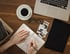 Kreativer Arbeitsplatz mit Notizen, Laptop und Kaffee bei QH Consulting