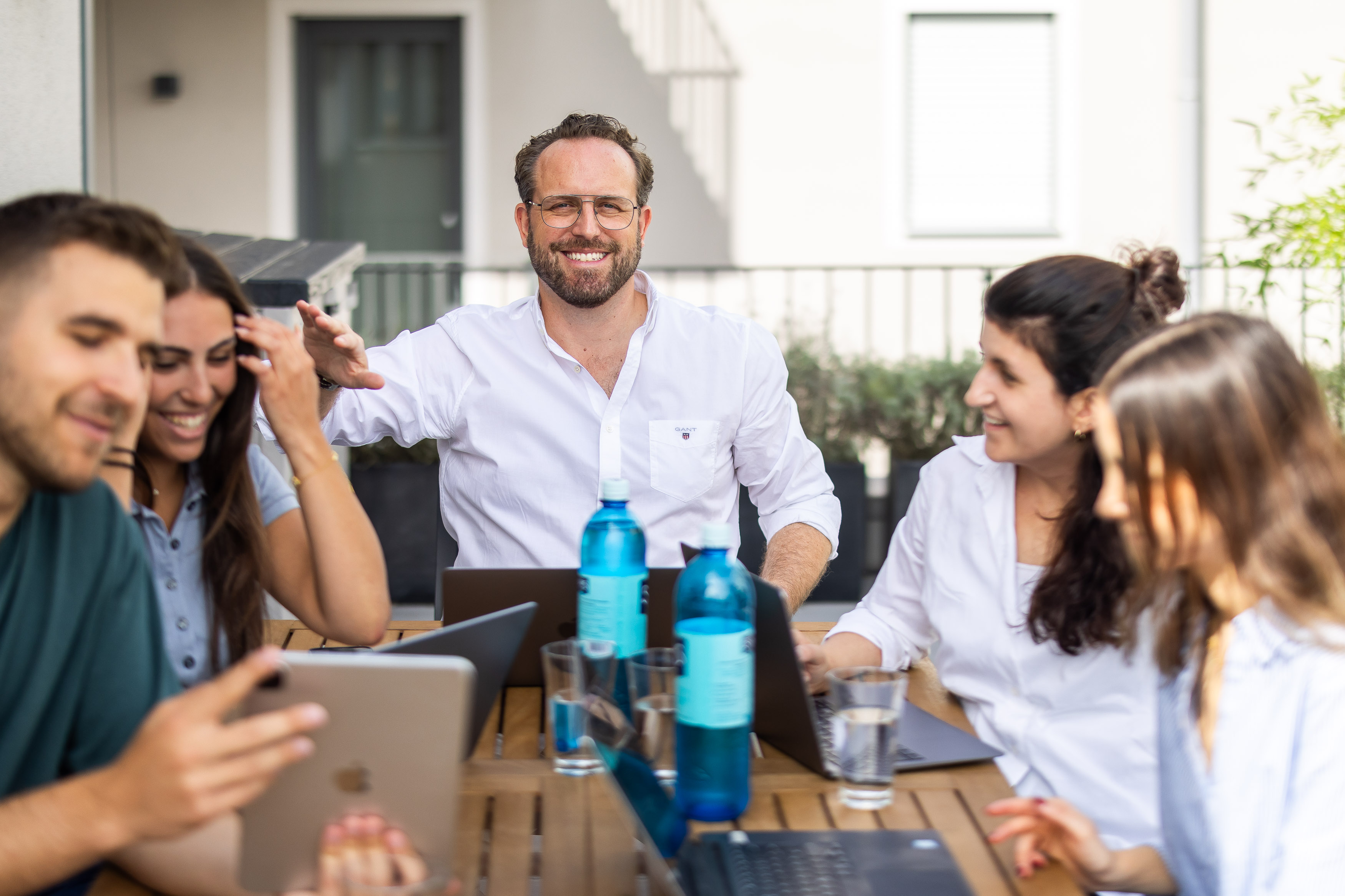 Das Team lacht bei einer Besprechung auf der Terrasse