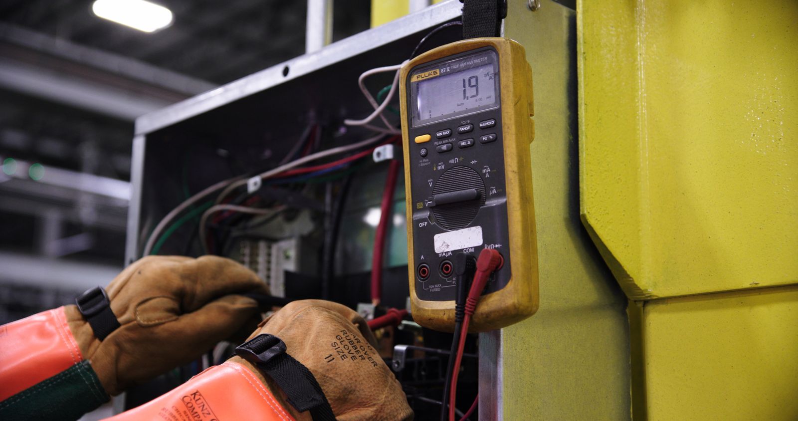 Technician using a meter to test terminations inside an opened EV charger wiring compartment in Santa Clara, California