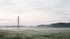 Strommast in einer nebligen Wiesenlandschaft am Morgen