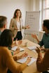Eine lächelnde Frau präsentiert vor einem Whiteboard mit den Stichpunkten "Goals" und "Strategy" einer Gruppe am Tisch.