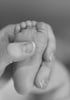 Zarte Hände einer Mutter massieren behutsam die Füße eines Babys – liebevolle Berührung bei der Babymassage.