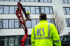 Ein Mann in einer gelben Jacke mit "KS"-Logo blickt auf einen Kollegen in einem Hubsteiger vor einem Gebäude.