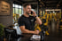 Mann in schwarzem T-Shirt telefoniert an der Rezeption des "TEMPLE GYM DRESDEN" Fitnessstudios.