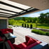 Moderne Terrasse mit weißer Pergola, roten Loungemöbeln und Blick auf grüne Landschaft.
