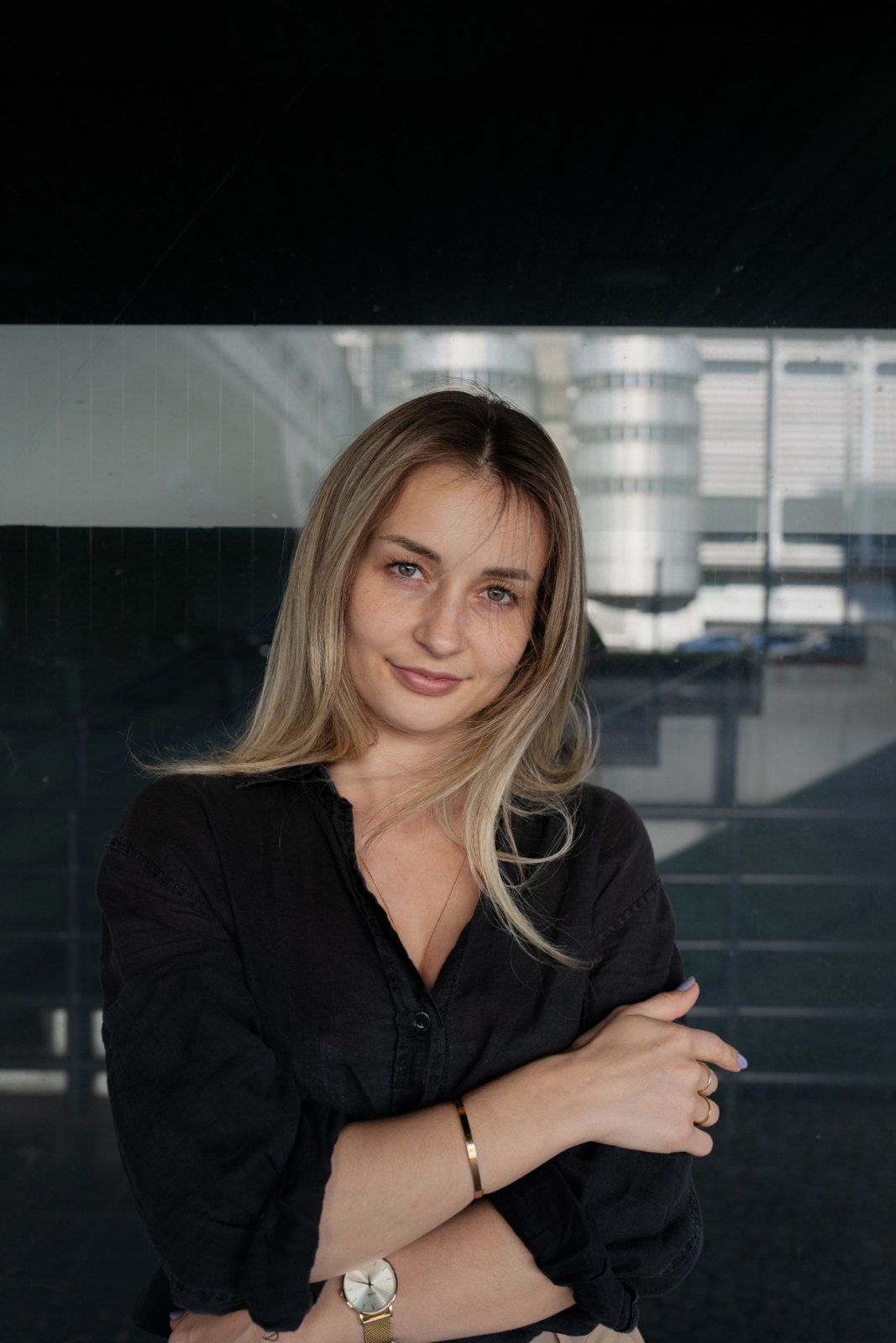 Tatjana Schäfer in schwarzer Bluse mit verschränkten Armen vor einer Glasfassade
