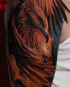 Detailreiches Tattoo eines Phönix in Orange- und Brauntönen mit Flammen auf einem Oberarm.