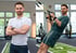 Ein Fitnesstrainer im weißen Poloshirt mit verschränkten Armen und beim TRX-Training im Fitnessstudio.