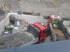 Zwei rote Kipper entladen Schotter auf einer Baustelle mit weißen Blockwänden.