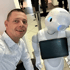 Ein lächelnder Mann im Hemd macht ein Selfie mit einem weißen Roboter mit Bildschirm.