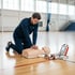 Herzdruckmassage an einer Übungspuppe neben einem AED