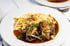 Zwiebelrostbraten mit Röstzwiebeln, dunkler Soße und Spätzle auf einem weißen Teller.