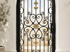 Ein schwarzes schmiedeeisernes Tor mit goldenen Ornamenten und Schnörkeln in einem weißen Torbogen.