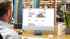 Mann sitzt am Schreibtisch und schaut auf einen Computermonitor mit einer Webseite.