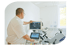 Ein Arzt bedient ein Echokardiographiegerät, das ein Herzbild auf dem Monitor anzeigt, neben einem Ergometer.