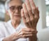 Elderly woman holding wrist, showing signs of neuropathy.