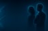Zwei Personen, eine Frau und ein Mann, als leuchtende blaue Silhouetten auf dunklem Hintergrund.