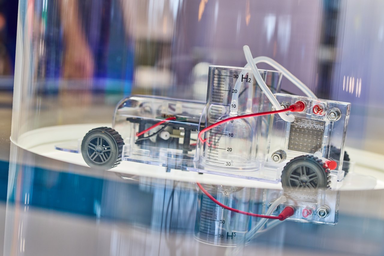 Haptisches Exponat: Ein transparentes Wasserstoff-Modellfahrzeug mit sichtbarer Elektrolysezelle und H2-Anzeige veranschaulicht, wie grüner Wasserstoff als Energieträger funktioniert