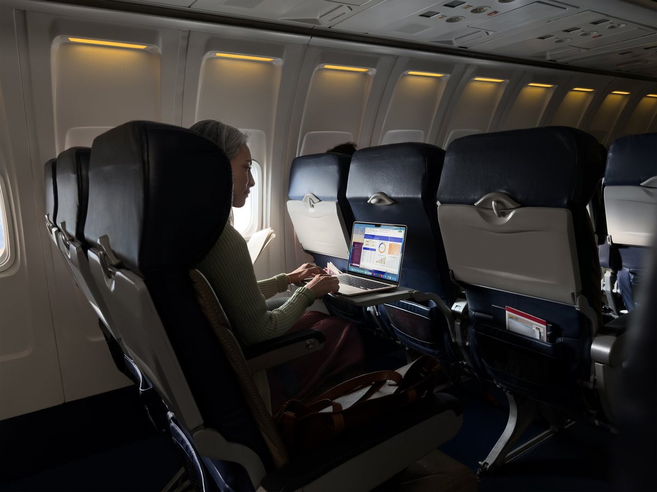 Person arbeitet in einem Flugzeug an einem MacBook Air