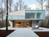 Modernes Einfamilienhaus mit Flachdach, großen Glasflächen und minimalistischer Fassadengestaltung – eingebettet in eine ruhige Waldlandschaft für zeitgemäßes Wohnen.