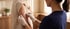 A healthcare worker wearing white gloves applies a transparent bandage to a patient's upper arm.