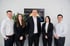 Das Finanz Strategie Team, drei Männer und zwei Frauen, stehen vor einem Logo an einer weißen Wand.