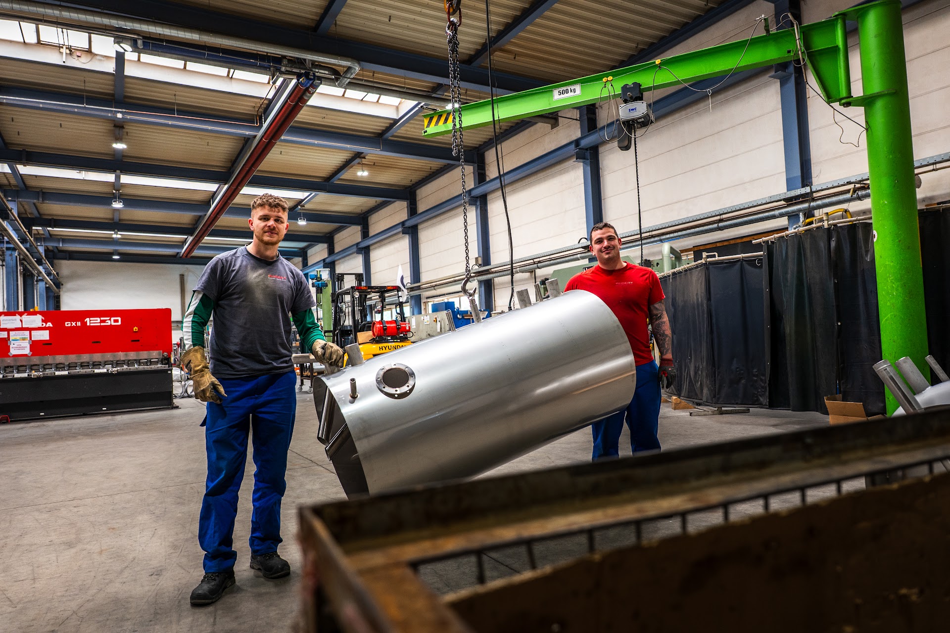Zwei Mitarbeiter von RUDERT bewegen einen Edelstahl-Warmwasserspeicher in der Produktionshalle in Crimmitschau