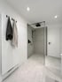 Modernes Badezimmer mit grauen Fliesen, begehbarer Dusche mit schwarzer Armatur und Handtuchhalter.