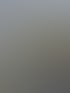 Blick von oben auf einen Mobilfunkmast mit Füßen, Kabeln und einer Herbstlandschaft mit einem Dorf im Hintergrund.