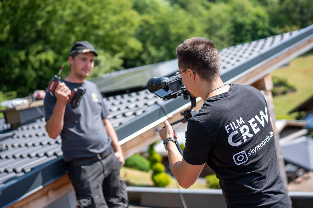 Kameramann von Skyrecords filmt einen Handwerker bei der Montage auf einem Dach mit Photovoltaikanlage