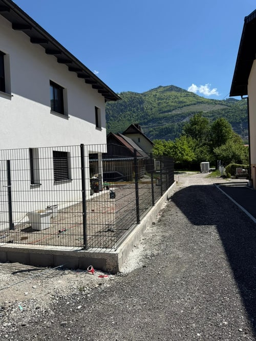 Fertiggestellter Weg an einem Neubau mit Bergen im Hintergrund