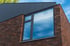 Fassadenecke eines modernen Gebäudes mit roten Ziegeln und einem anthrazitfarbenen Fenster.