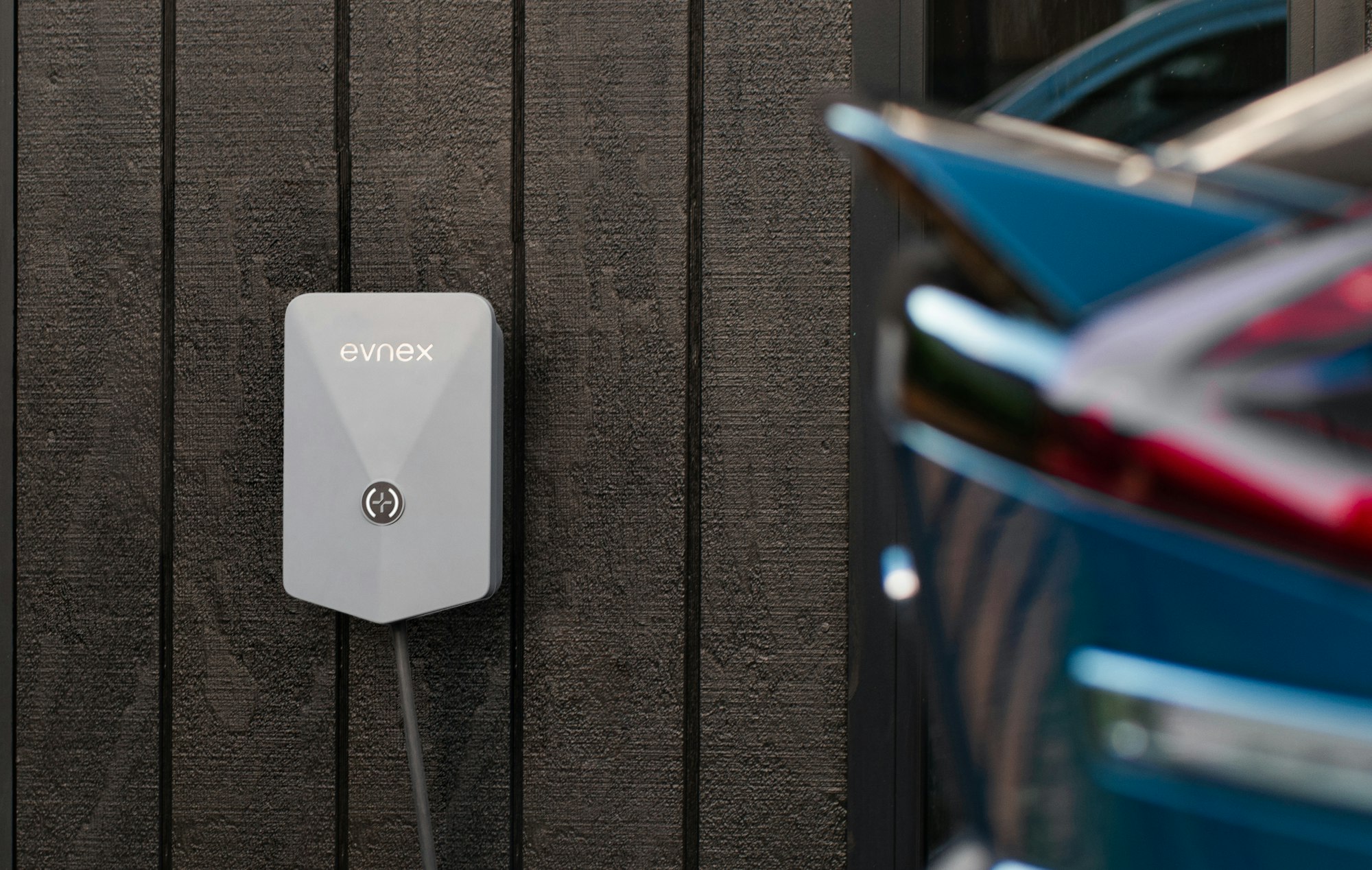 Electric vehicle plugged into a wall-mounted connector in a garage