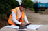Christian Roßmann berechnet Daten auf einer Baustelle mit Tablet und Bauplänen in orangener Sicherheitsweste.