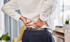Hands holding an aching lower back.