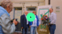 Drei Personen vor einer Steuerkanzlei mit Blumenstrauß und 50-Jahre-Jubiläumsbanner, während sie fotografiert werden.