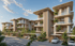 Modern multi-story residential buildings with curved facades, balconies, lush green trees, and covered parking spaces.