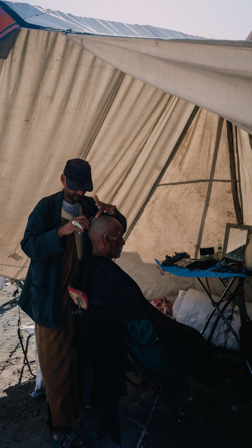 Friseur arbeitet unter einem Zeltdach auf dem Wochenmarkt