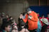 Ein Mann in einem orangefarbenen Kapuzenpulli mit Mikrofon gibt Kindern in einer Turnhalle ein High-Five.