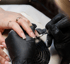 Hände in schwarzen Handschuhen bearbeiten Fingernägel mit einer elektrischen Nagelfräse während einer Maniküre.