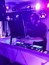 DJ Weihrauch live bei Event mit violettem Licht und professionellem DJ-Equipment