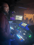 DJ Alexander Stephan konzentriert am Mischpult mit Lichtshow im Hintergrund