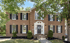 Large two-story brick house with black shutters, white trim, and a white wreath on the front door.