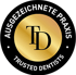 Schwarzes Siegel mit goldenem Kreis, darin "TD" und die Aufschrift "AUSGEZEICHNETE PRAXIS TRUSTED DENTISTS".